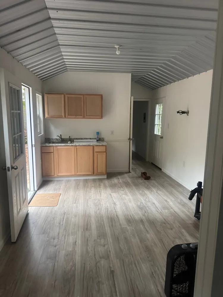 Empty remodeled room with new plank flooring and a small kitchenette