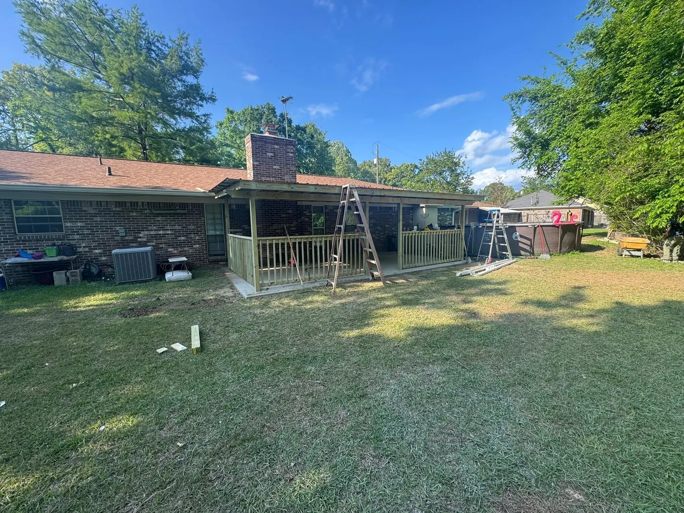 Screened porch framed in treated lumber behind a brick ranch house