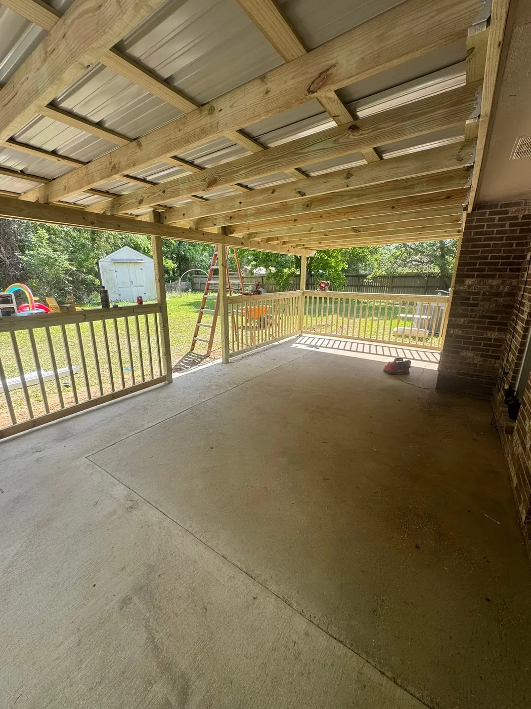 Underside of a new porch roof with exposed wood framing over a concrete slab