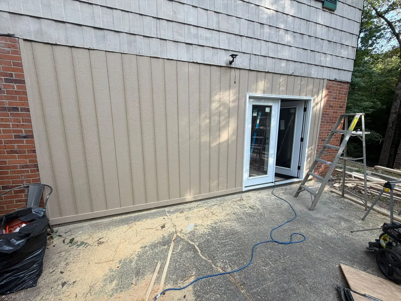 Tan board and batten siding with new double doors on a brick home