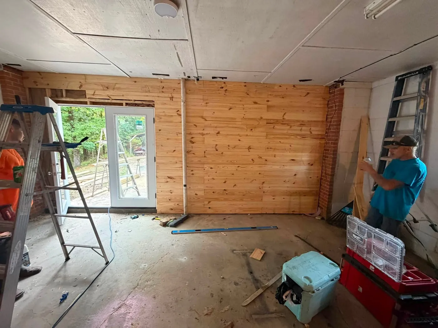 Interior wall clad in wood planks with a crew member working beside a ladder