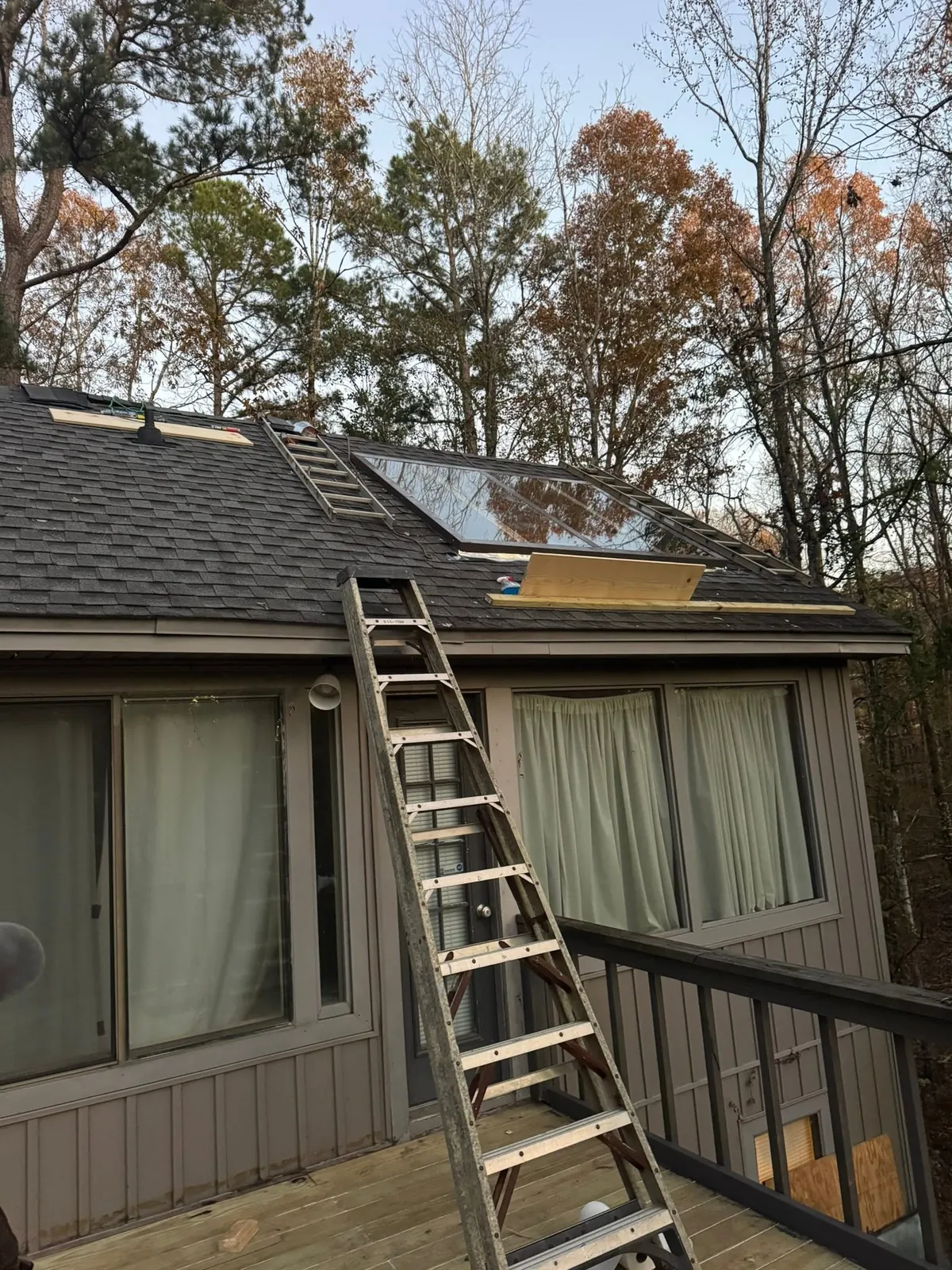 Ladder leaning against a house with a skylight opening cut into the roof